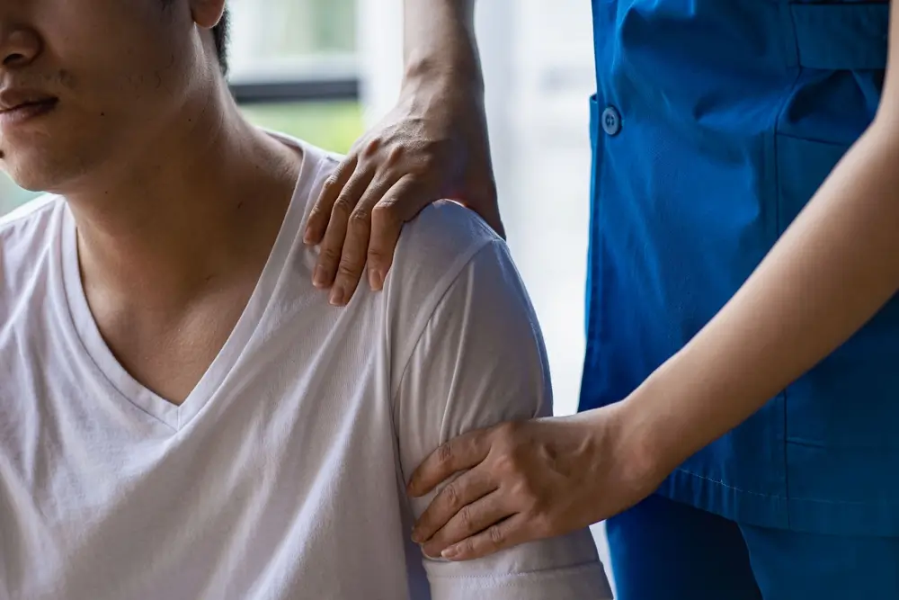Jeune homme asiatique faisant de la physiothérapie et recherchant des conseils sur la douleur musculaire avec l'épaule, membres dans un centre de réadaptation.