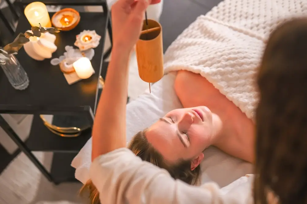 Massage du visage et diapason thérapie sonore dans le spa aux chandelles, soins holistiques rituel de bien-être, relaxation et soulagement du stress, soins personnels, équilibre énergétique.