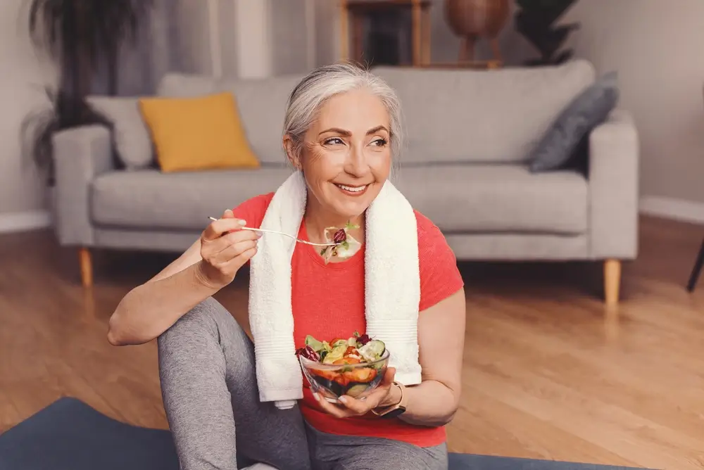 Femme Blanche Senior Souriante Appréciant Salade Saine Après L'Entraînement À La Maison, Concept De Perte De Poids